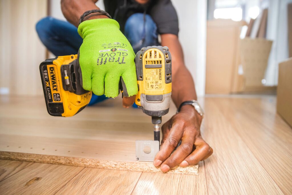 pexels photo 1249611 1249611 Man using a power drill for home improvement on a wooden floor with precision.