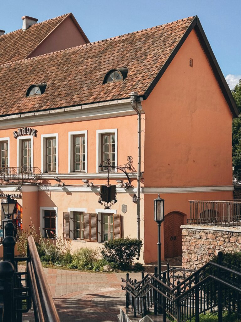 Charming peach-colored historical building with vintage design and lush garden, perfect for architecture enthusiasts.